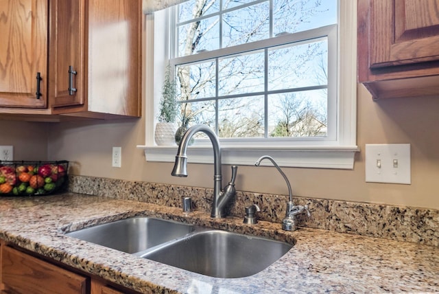 room details with light stone counters, brown cabinets, and a sink