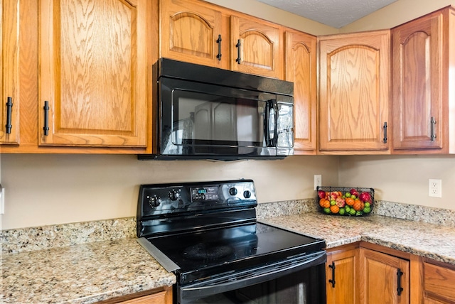 kitchen with light stone counters, brown cabinetry, and black appliances