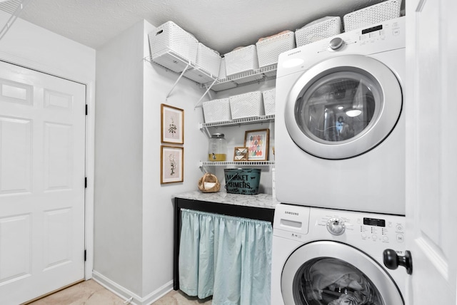 laundry area with laundry area, baseboards, a textured ceiling, and stacked washer and clothes dryer