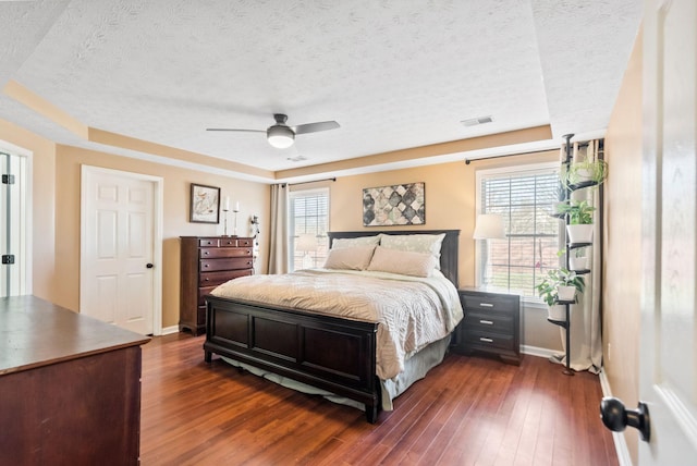 bedroom with dark wood-style flooring, visible vents, a textured ceiling, and baseboards