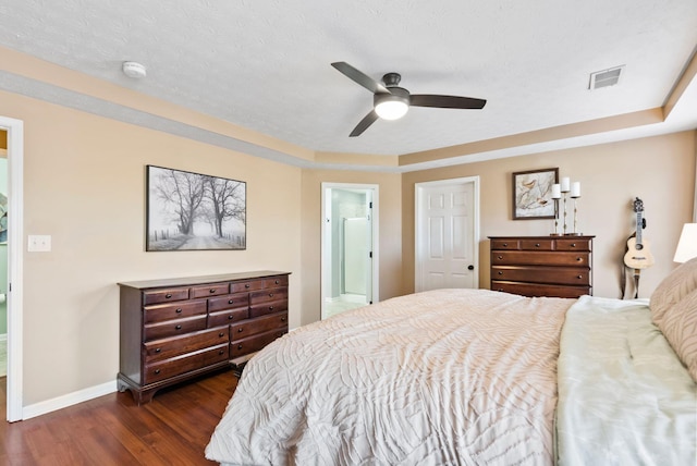 bedroom with dark wood finished floors, visible vents, ceiling fan, a textured ceiling, and baseboards