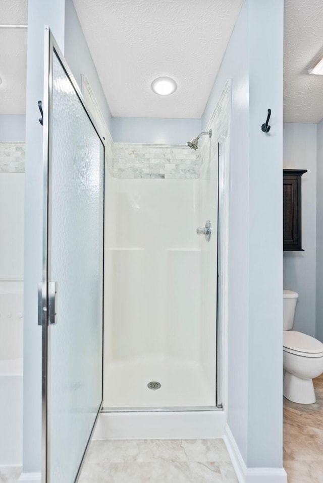 full bathroom featuring a stall shower, a textured ceiling, and toilet