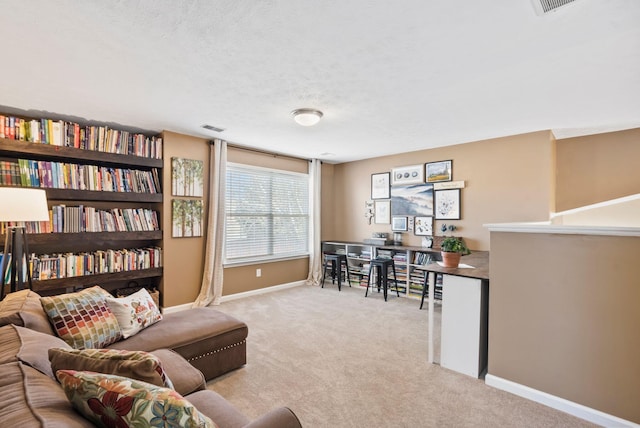 living area with baseboards, visible vents, a textured ceiling, and light colored carpet