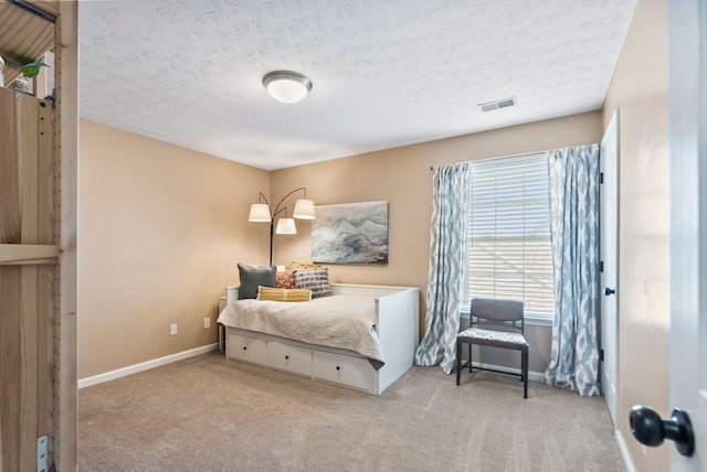 bedroom with light colored carpet, visible vents, a textured ceiling, and baseboards