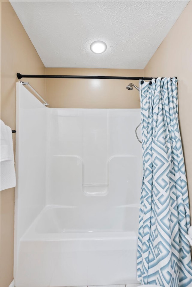 full bath featuring a textured ceiling and shower / bathtub combination with curtain