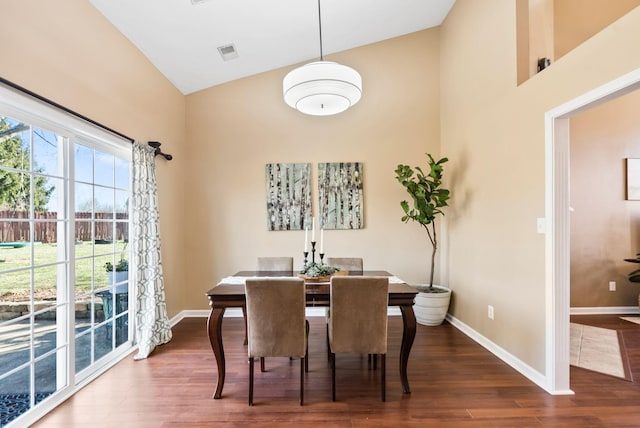 dining room featuring a high ceiling, dark wood-style flooring, visible vents, and baseboards