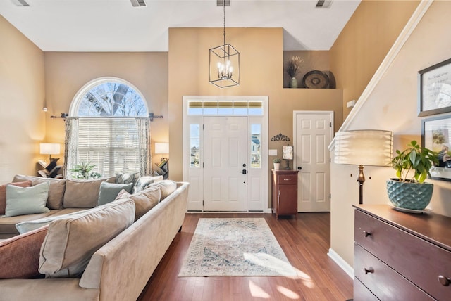 entryway featuring a towering ceiling, visible vents, dark wood finished floors, and a chandelier