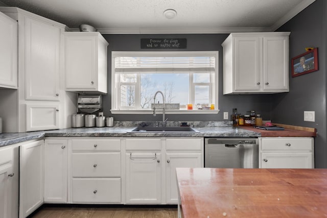 kitchen featuring crown molding, stainless steel dishwasher, white cabinets, a sink, and a textured ceiling