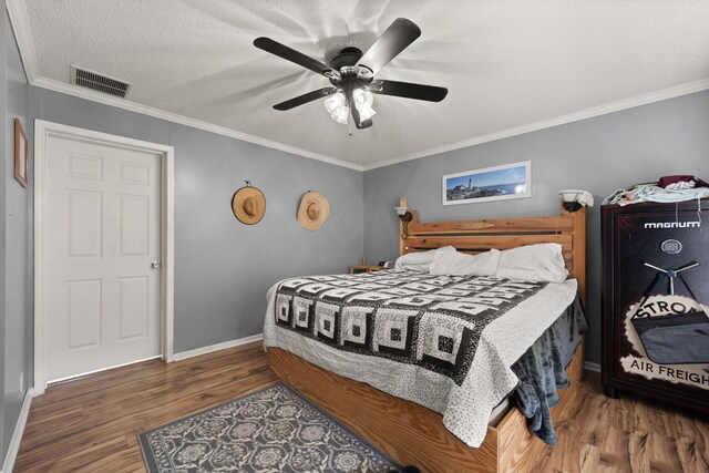 bedroom featuring a textured ceiling, wood finished floors, visible vents, baseboards, and crown molding