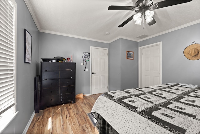 bedroom with ornamental molding, baseboards, a textured ceiling, and light wood finished floors