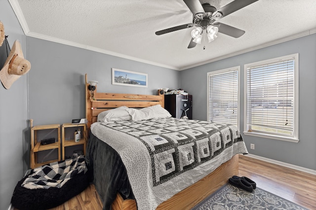 bedroom with a textured ceiling, ornamental molding, wood finished floors, and baseboards