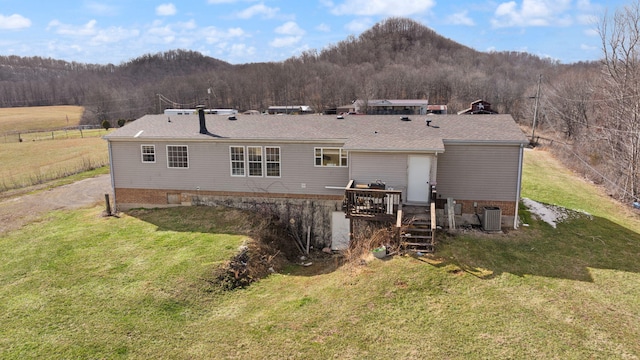 back of property featuring a deck with mountain view, a forest view, and a lawn