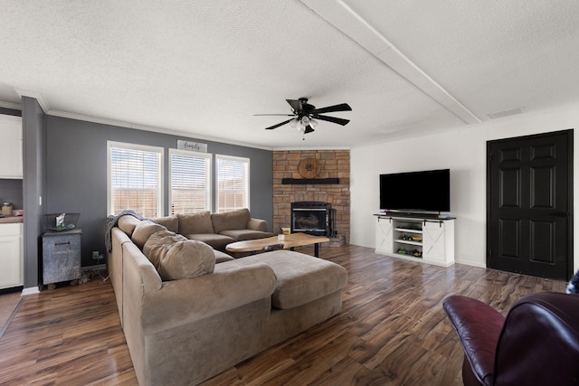 living room with dark wood-style floors, a stone fireplace, a textured ceiling, and a ceiling fan