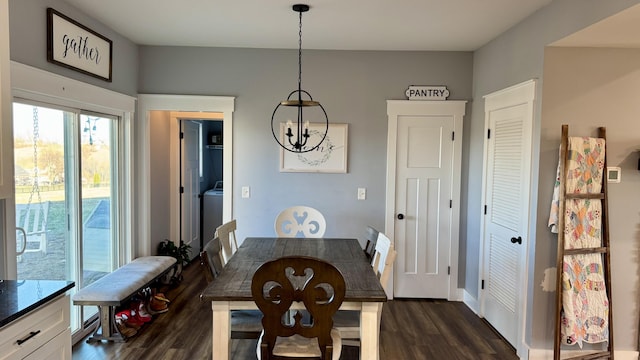 dining room featuring dark wood-type flooring, washer / clothes dryer, and a notable chandelier