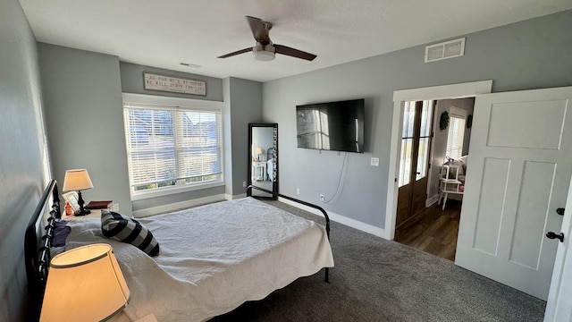 bedroom with a ceiling fan, dark carpet, visible vents, and baseboards