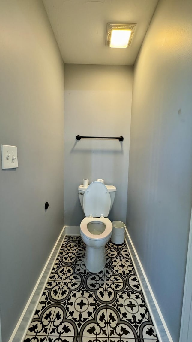 bathroom with toilet, baseboards, and tile patterned floors