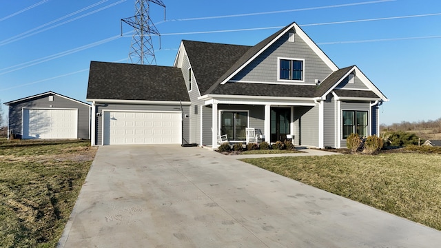 view of front of house with roof with shingles, a porch, concrete driveway, an attached garage, and a front lawn