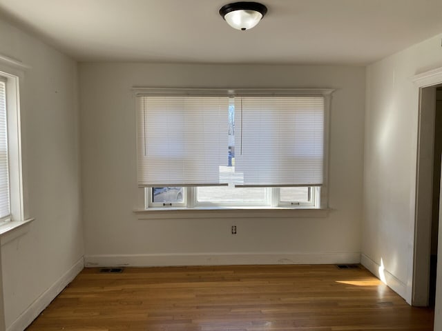 unfurnished room featuring visible vents, baseboards, and wood finished floors