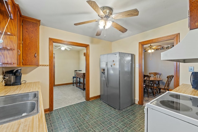 kitchen with electric range, baseboards, brown cabinetry, stainless steel refrigerator with ice dispenser, and a sink