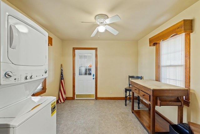 washroom featuring laundry area, ceiling fan, baseboards, and stacked washer and clothes dryer