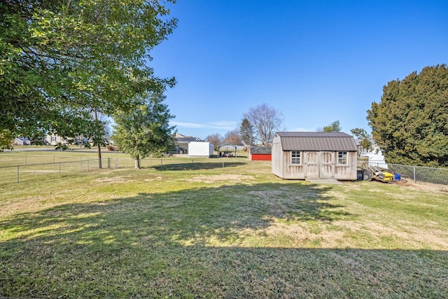 view of yard with a fenced backyard, a rural view, a storage unit, and an outbuilding