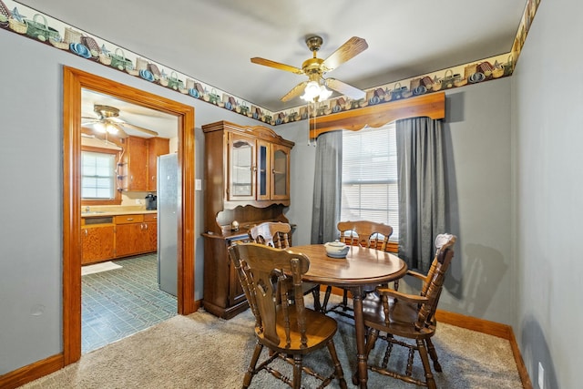 carpeted dining area with baseboards, a ceiling fan, and a healthy amount of sunlight