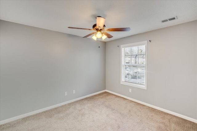 spare room with light carpet, baseboards, visible vents, and ceiling fan