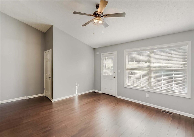 interior space featuring dark wood-type flooring, visible vents, vaulted ceiling, and baseboards