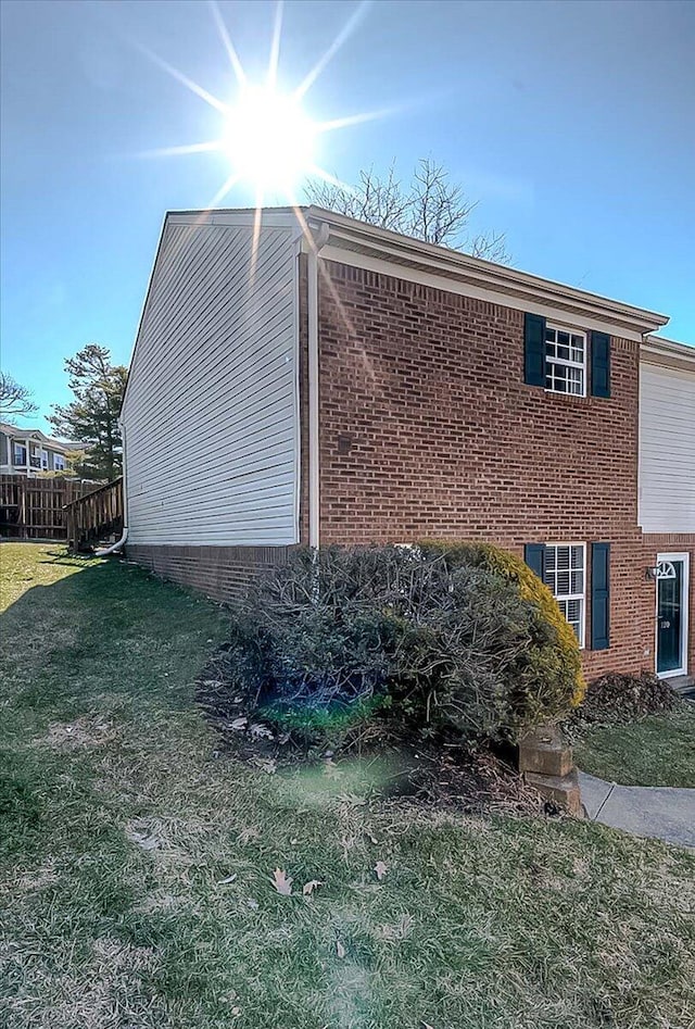 view of side of property with brick siding and a yard