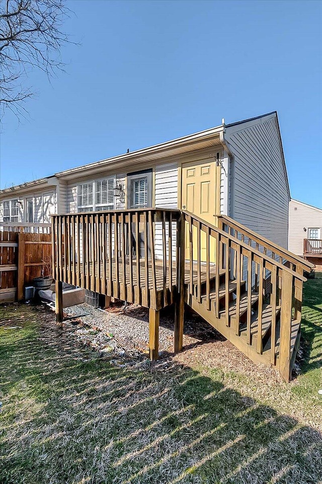 back of property with fence, a lawn, and a wooden deck