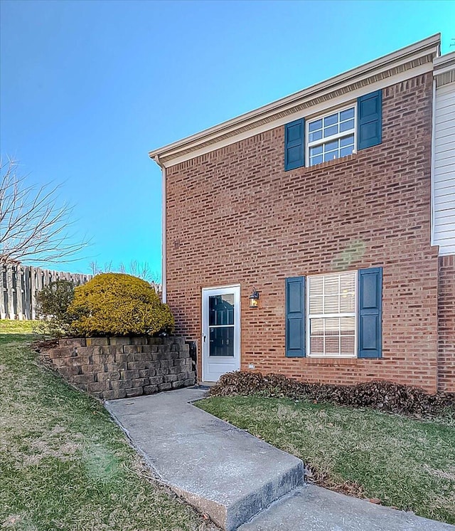 exterior space with brick siding, fence, a patio, and a yard