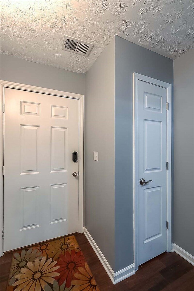 doorway featuring visible vents, dark wood finished floors, a textured ceiling, and baseboards