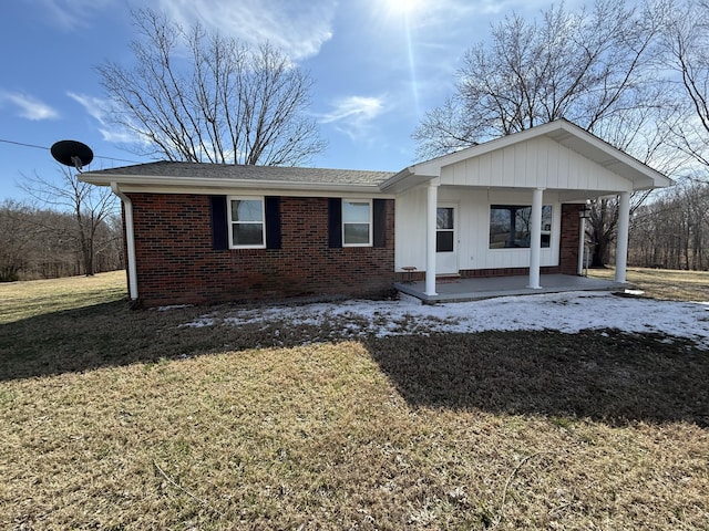 view of front of property featuring a front yard, covered porch, and brick siding