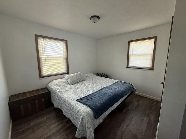 bedroom with dark wood-type flooring and baseboards