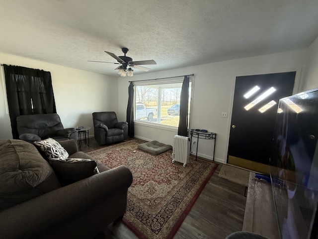 living room with a textured ceiling, baseboards, dark wood finished floors, and radiator