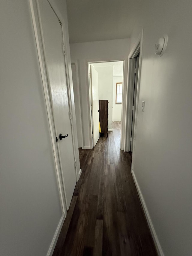 hall featuring dark wood-style flooring and baseboards