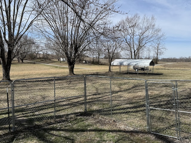 view of yard with a gate, fence, and a rural view