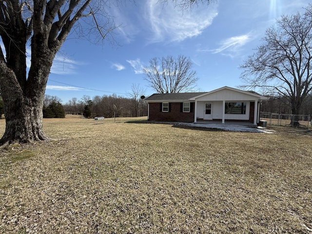 view of front of home with brick siding, a front yard, and fence