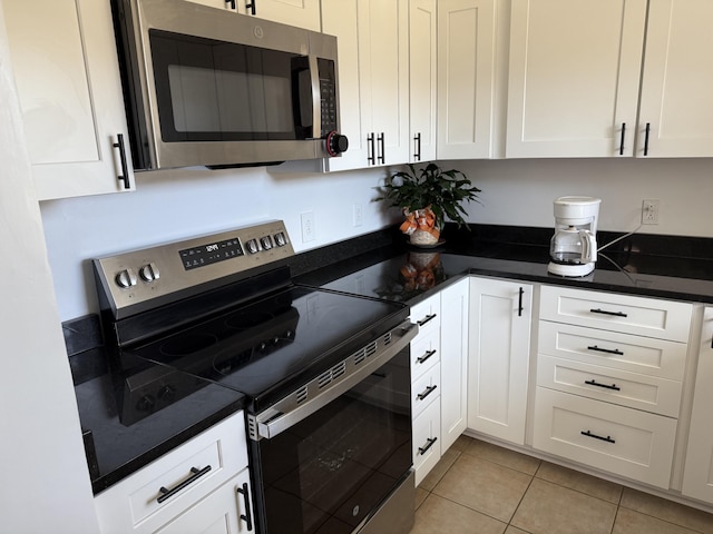 kitchen featuring appliances with stainless steel finishes, dark countertops, white cabinets, and light tile patterned floors