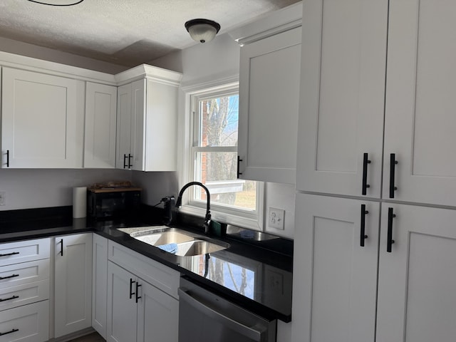 kitchen featuring a textured ceiling, a sink, white cabinetry, dishwasher, and dark countertops