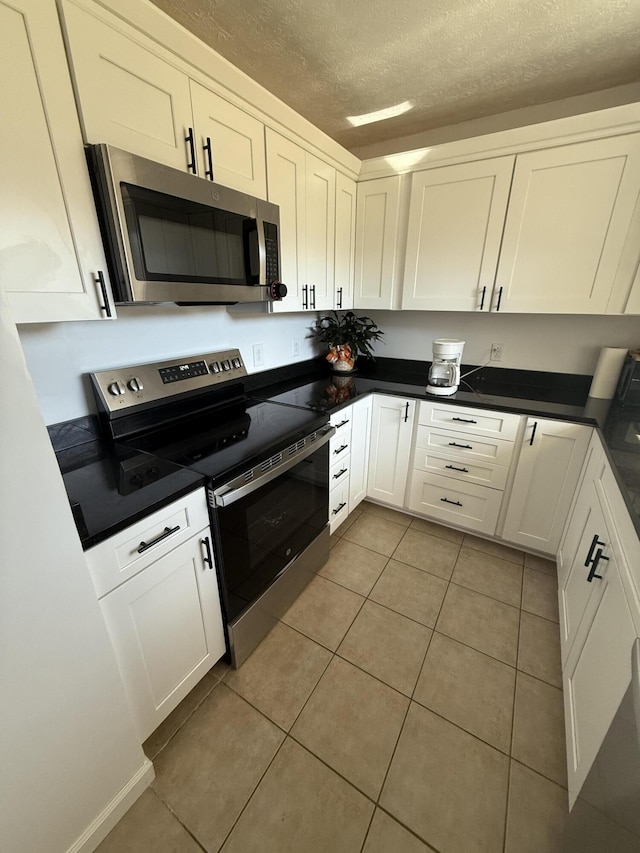 kitchen featuring stainless steel appliances, white cabinetry, and light tile patterned floors