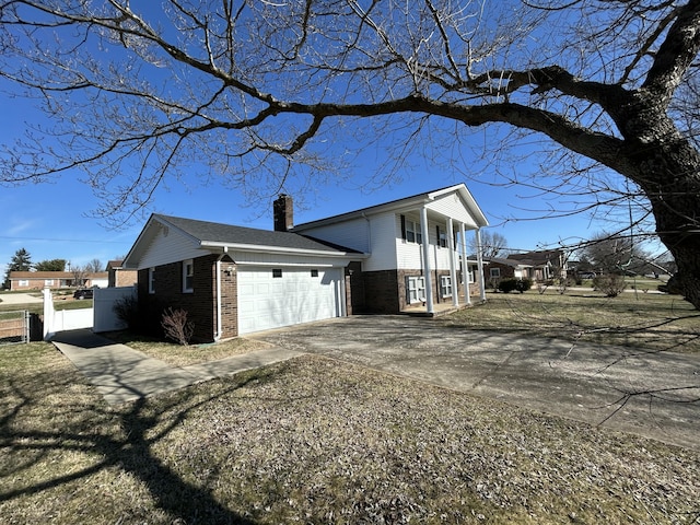 view of home's exterior featuring a garage, brick siding, fence, driveway, and a chimney