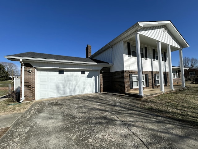 view of front facade with driveway, covered porch, an attached garage, and brick siding