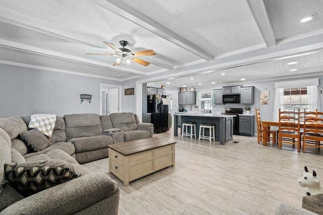 living area with crown molding, recessed lighting, beamed ceiling, and ceiling fan