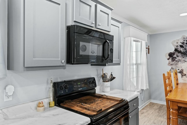 kitchen with light wood-type flooring, gray cabinetry, baseboards, and black appliances