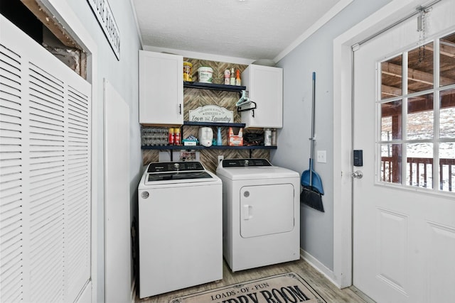 laundry area with washer and clothes dryer, cabinet space, light wood-style flooring, a textured ceiling, and baseboards