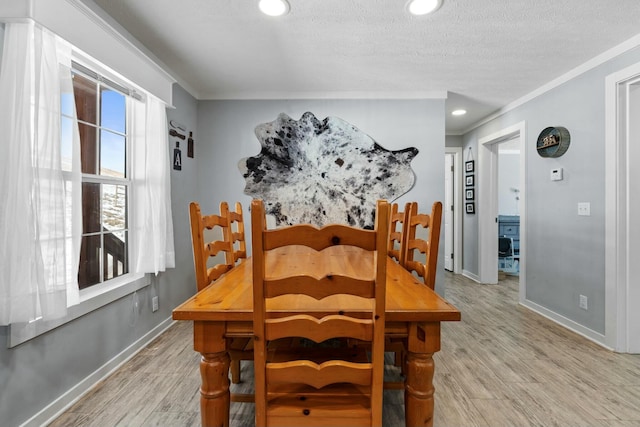 dining area featuring light wood finished floors, baseboards, and ornamental molding