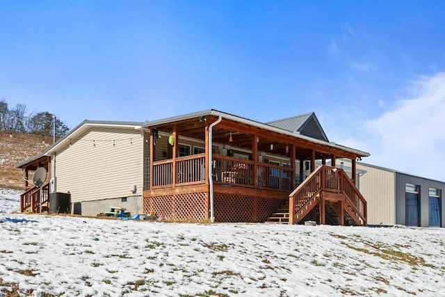 snow covered house featuring crawl space, metal roof, central air condition unit, and stairs