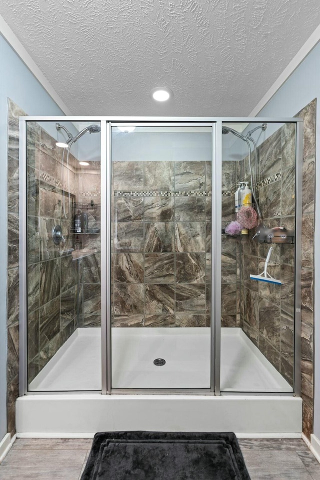 full bathroom with a stall shower, a textured ceiling, and wood finished floors