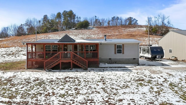 snow covered back of property featuring crawl space, metal roof, and stairs